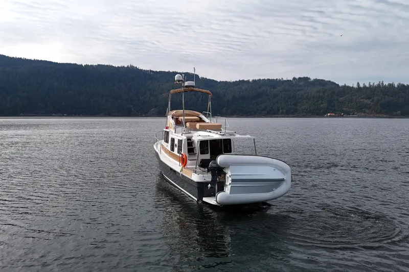  Yacht Photos Pics 2021 Ranger Tugs R-31 CB boat on calm water with forested hills in background.