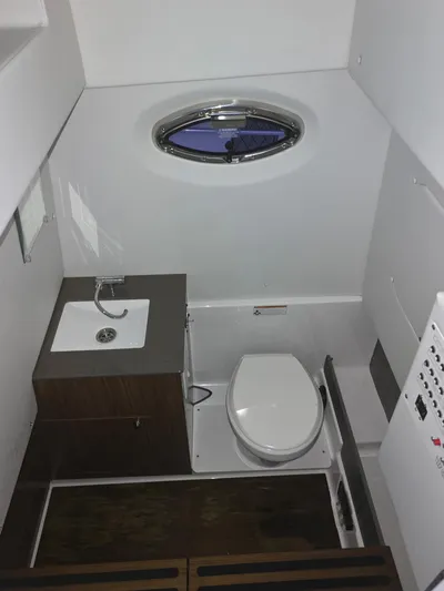 Even Or Odd Yacht Photos Pics 2023 Wellcraft 302 Fisherman boat bathroom with sink, toilet, and porthole window.