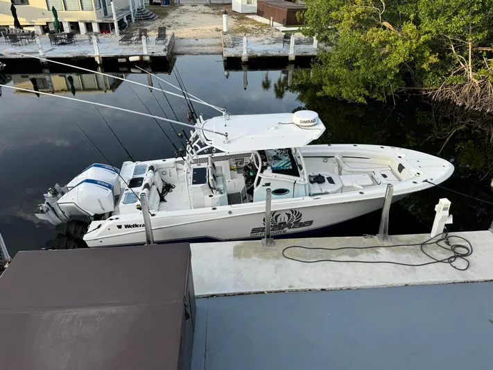 Even Or Odd Yacht Photos Pics 2023 Wellcraft 302 Fisherman boat docked by the water, equipped with fishing rods.