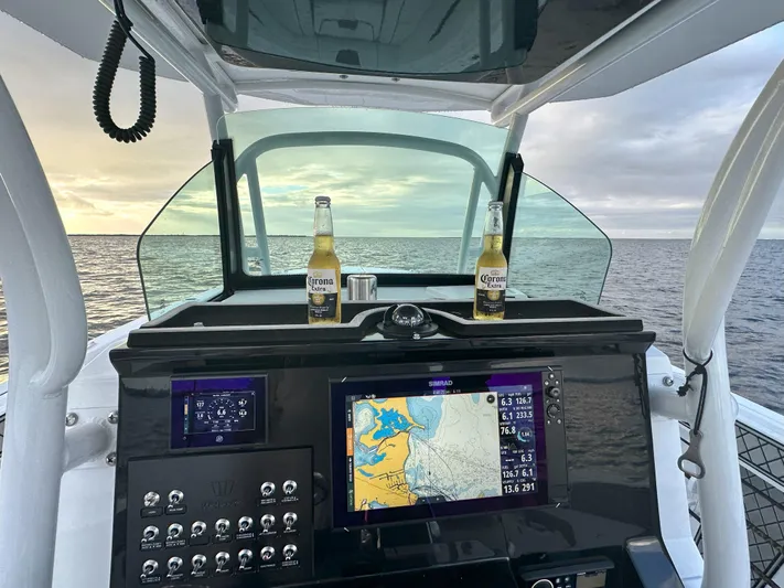 Even Or Odd Yacht Photos Pics 2023 Wellcraft 302 Fisherman dashboard with navigation system and two beer bottles at sea.