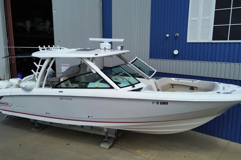  Yacht Photos Pics 2017 Boston Whaler 320 Vantage boat docked near a blue and gray building.