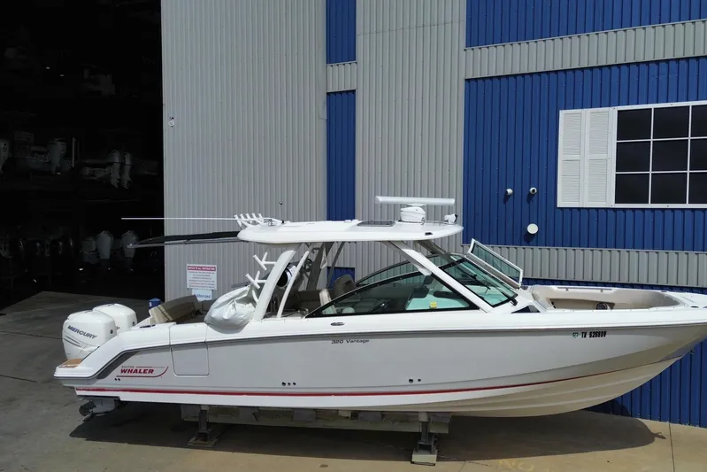  Yacht Photos Pics 2017 Boston Whaler 320 Vantage boat docked near a blue and gray building.