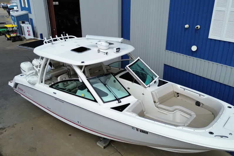  Yacht Photos Pics 2017 Boston Whaler 320 Vantage boat docked near a blue building.