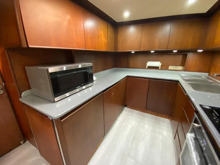  Yacht Photos Pics Modern kitchen with wooden cabinets, microwave, and sleek countertops in a 2007 Rodriquez 80 Widebody yacht.