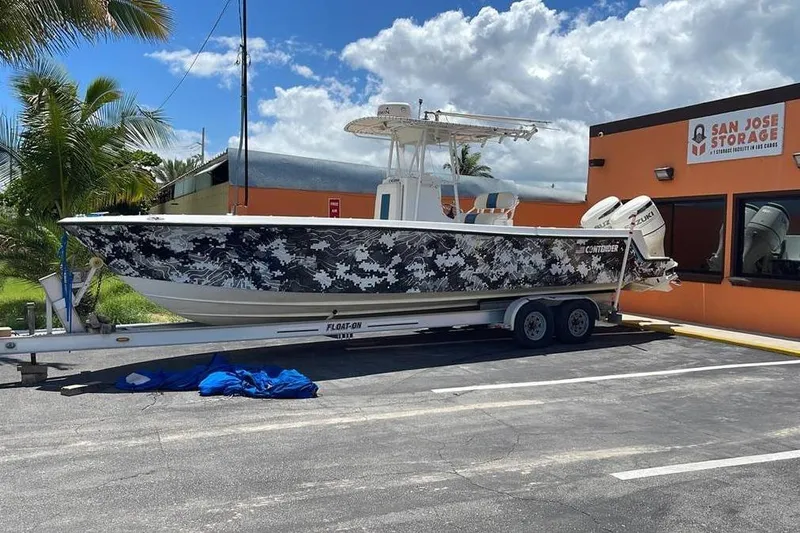  Yacht Photos Pics 2001 Contender 27 Open CC boat with camouflage design on trailer near storage facility.