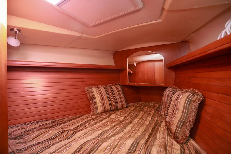 Matt's Dinghy Yacht Photos Pics Cozy cabin interior of 2009 Hunter 45 Center Cockpit with wood paneling and striped bedding.