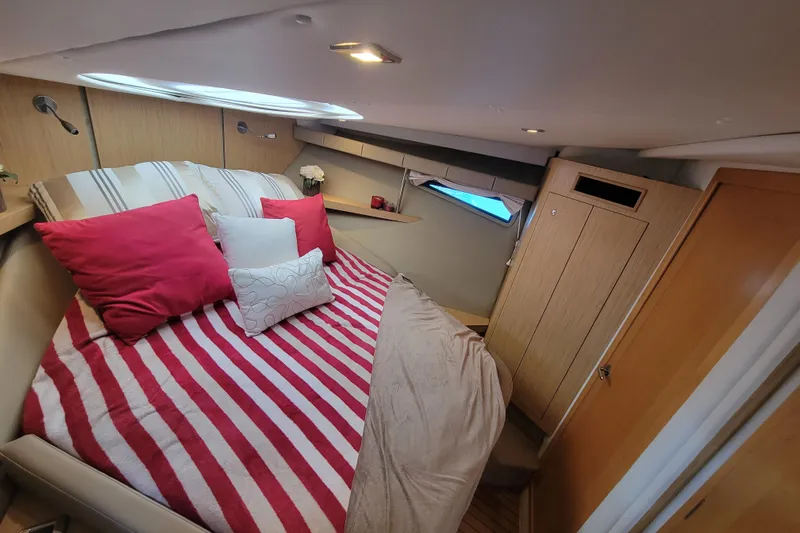 Isabella IV Yacht Photos Pics Cozy cabin interior of 2012 Four Winns V435 yacht with striped bedding and red pillows.