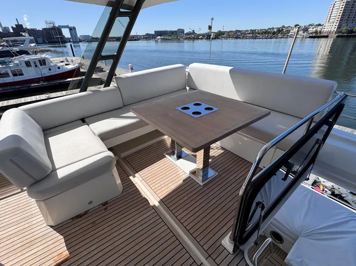  Yacht Photos Pics Luxurious 2023 Prestige 520 F-Line yacht deck with seating and table, overlooking marina.