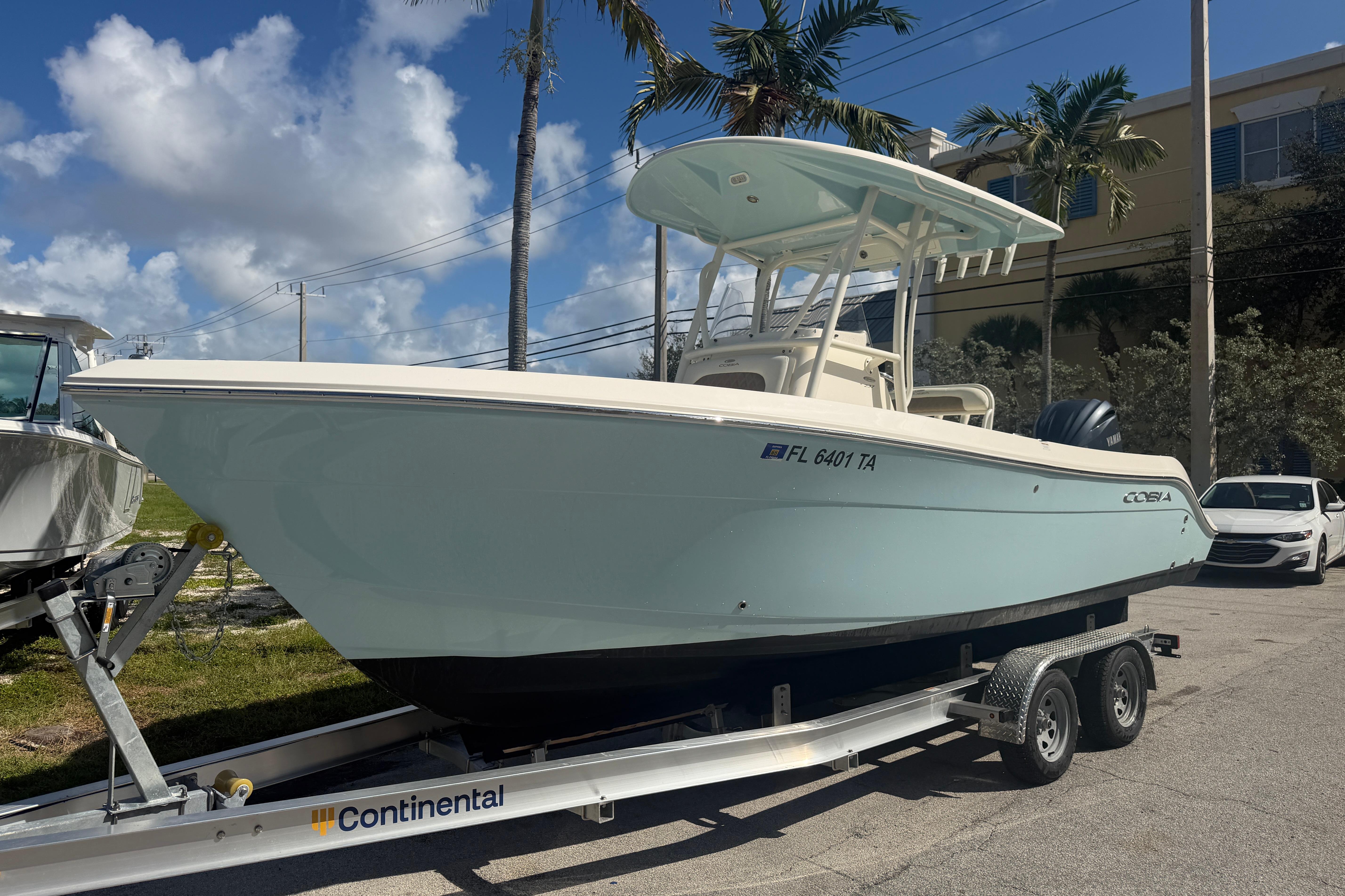 2021 Cobia 237 Center Console boat on trailer, parked outdoors under blue sky.