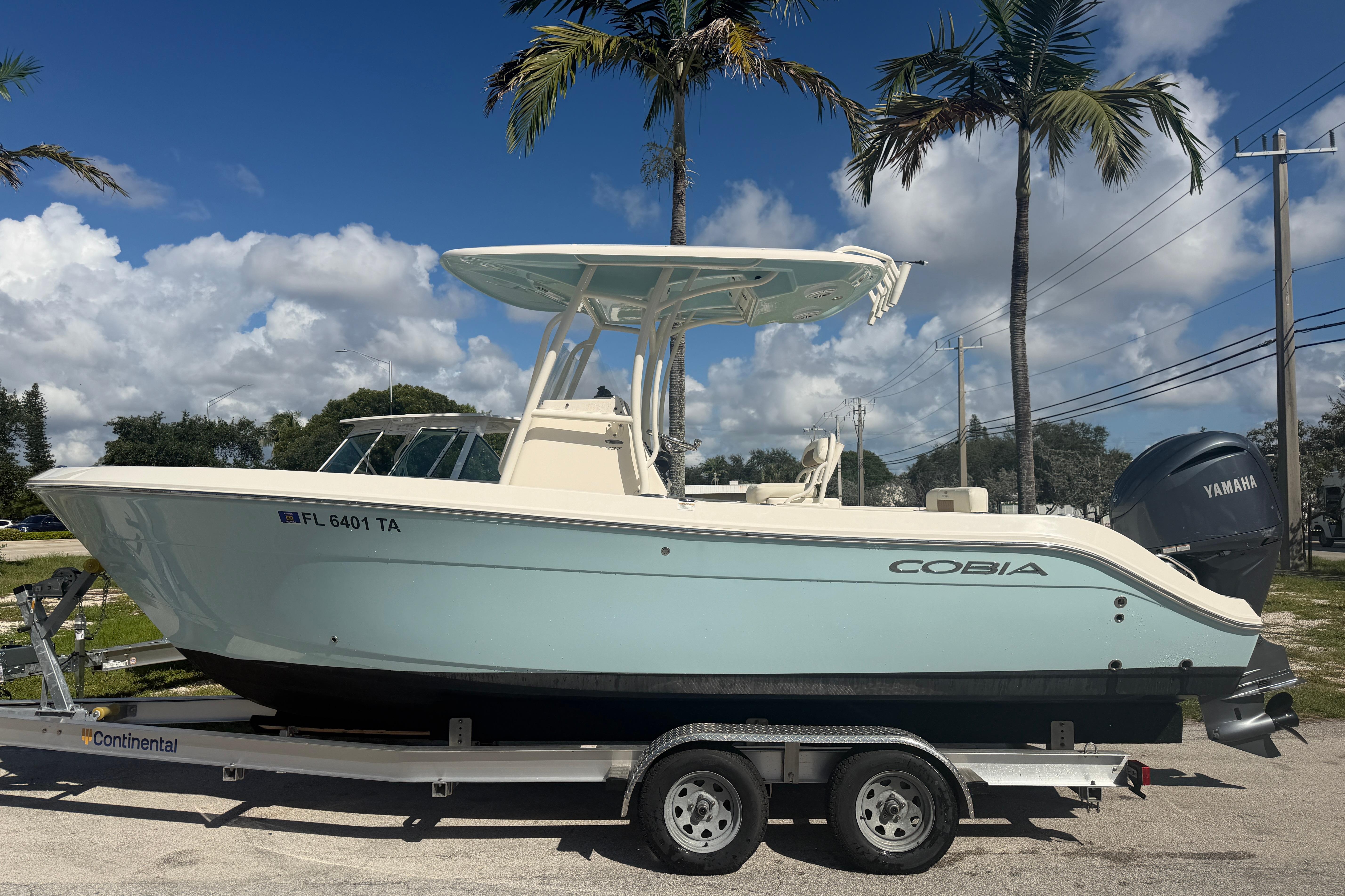 2021 Cobia 237 Center Console boat on trailer, parked under palm trees.