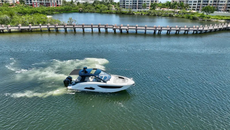  Yacht Photos Pics 2024 Sea Ray Sundancer 370 Outboard cruising on a scenic waterway with lush greenery.