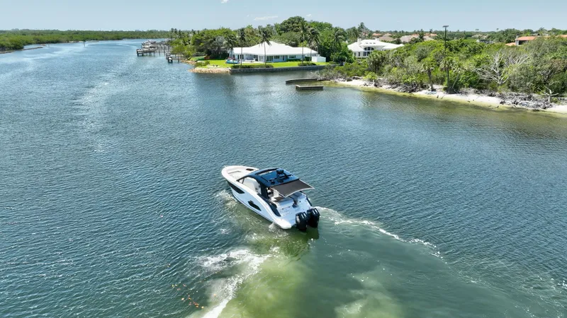  Yacht Photos Pics 2024 Sea Ray Sundancer 370 Outboard cruising on a scenic river near lush greenery.