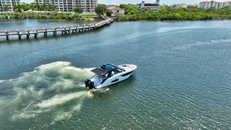  Yacht Photos Pics 2024 Sea Ray Sundancer 370 Outboard cruising on a scenic waterway near a bridge.
