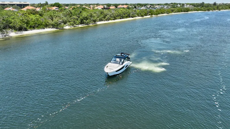  Yacht Photos Pics 2024 Sea Ray Sundancer 370 Outboard cruising on a scenic river near lush greenery.