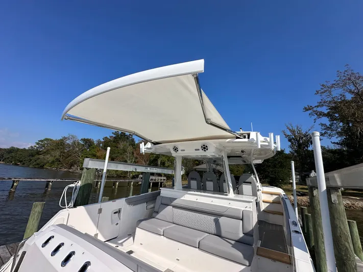  Yacht Photos Pics 2026 Regal 38 SAV boat with canopy, docked by a scenic waterfront.