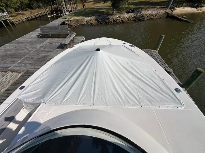  Yacht Photos Pics 2026 Regal 38 SAV boat docked, covered with a white tarp, near a wooden pier.