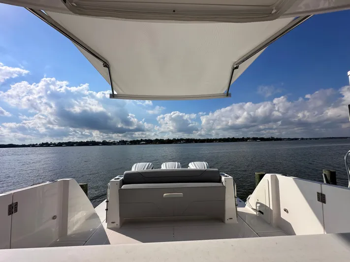  Yacht Photos Pics 2026 Regal 38 SAV yacht with canopy, overlooking serene water and cloudy sky.