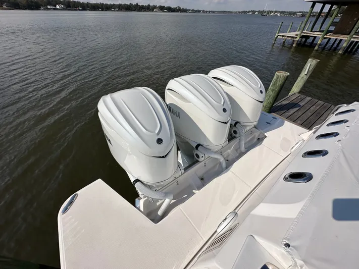  Yacht Photos Pics Triple Yamaha outboard engines on a 2026 Regal 38 SAV boat docked by the water.
