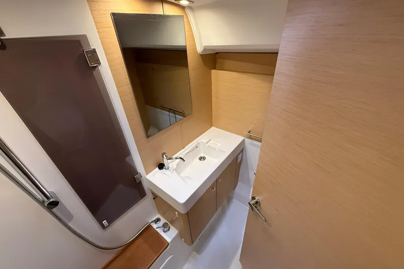 Shaboom Yacht Photos Pics 2017 Jeanneau Sun Odyssey 479 bathroom with modern sink, mirror, and wooden cabinetry.