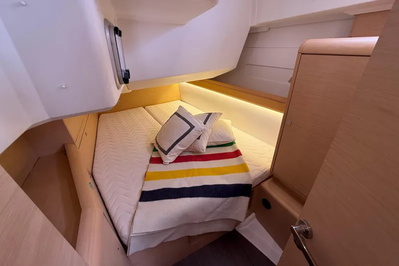 Shaboom Yacht Photos Pics Cozy cabin interior of 2017 Jeanneau Sun Odyssey 479 yacht with striped blanket.