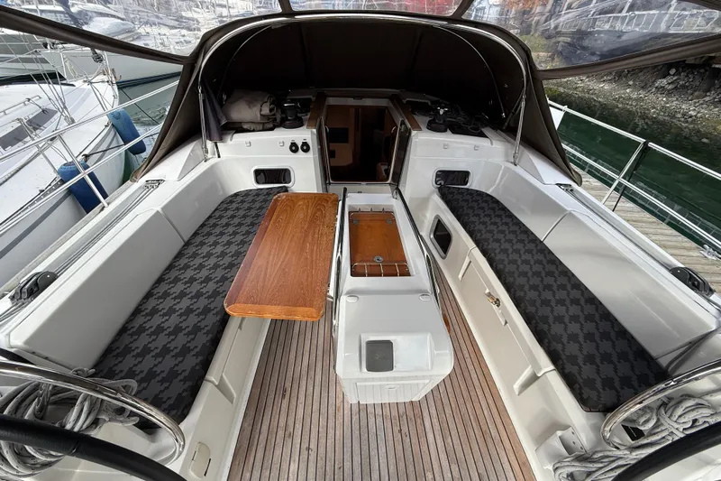 Shaboom Yacht Photos Pics Cockpit of 2017 Jeanneau Sun Odyssey 479 sailboat with seating and wooden table.