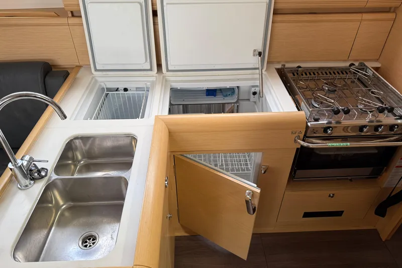 Shaboom Yacht Photos Pics Modern kitchen in 2017 Jeanneau Sun Odyssey 479 yacht with stove, sink, and fridge.