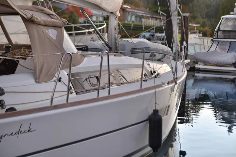 Mayne Deck Yacht Photos Pics 2019 Dufour 382 Grand Large yacht docked in a marina, reflecting on calm water.