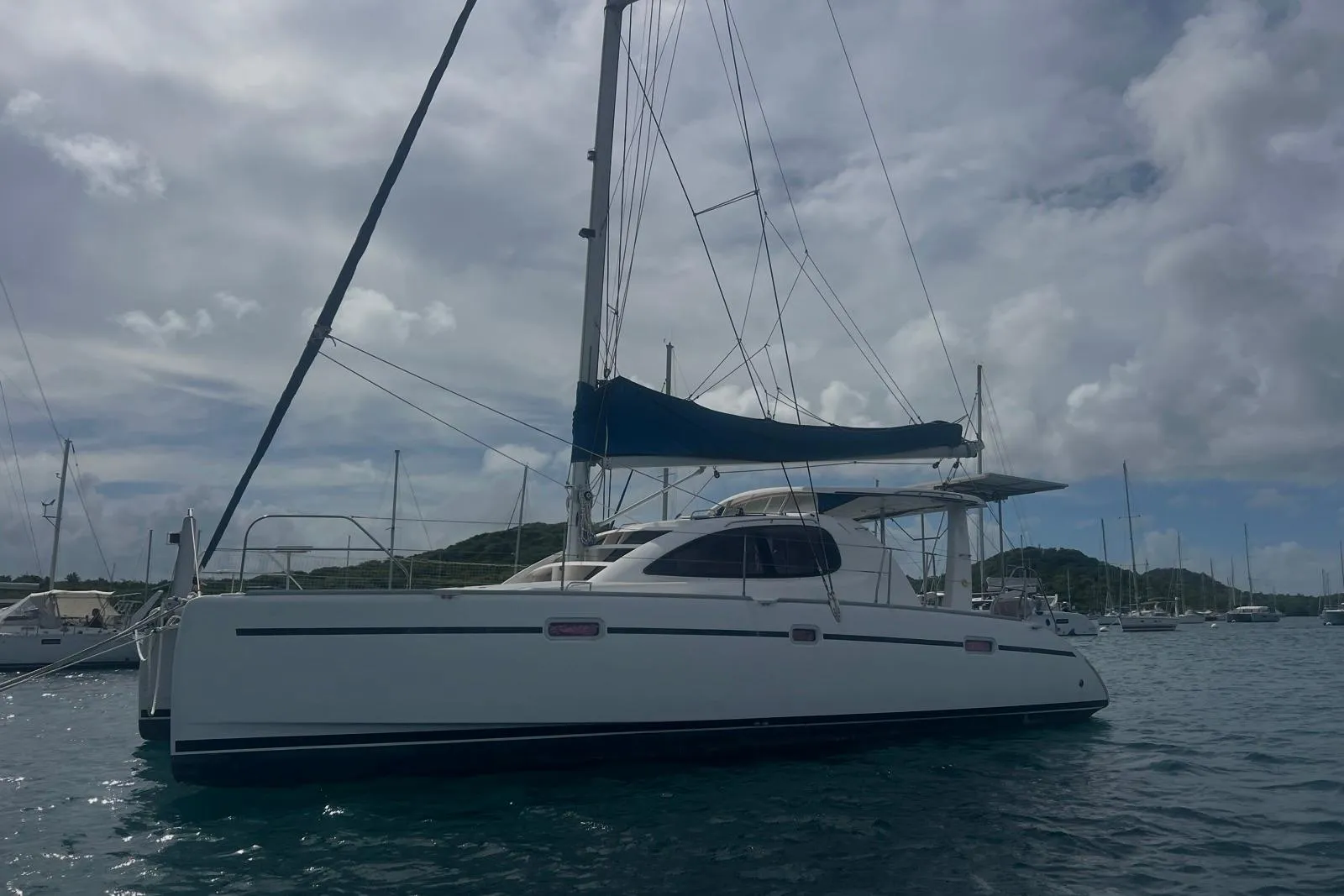 2005 Leopard 40 catamaran anchored in a serene harbor under cloudy skies.