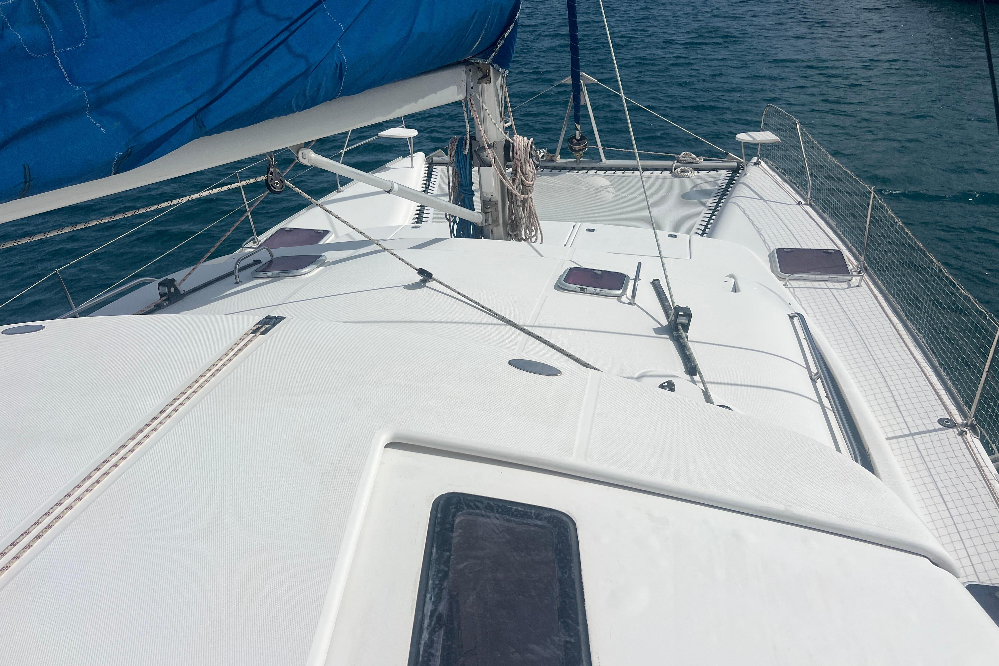 2005 Leopard 40 catamaran deck with blue sail, on calm sea.