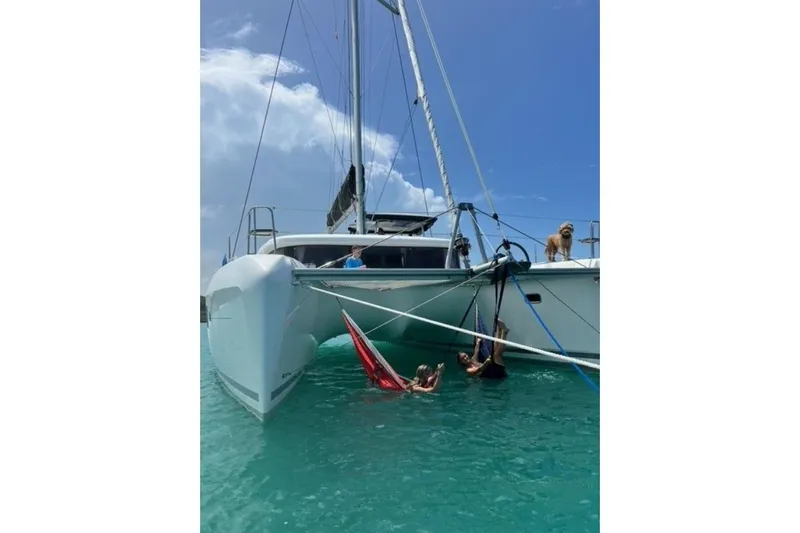 Never Say Never Yacht Photos Pics 2017 Lagoon 42 catamaran with people relaxing in hammocks and a dog on deck.