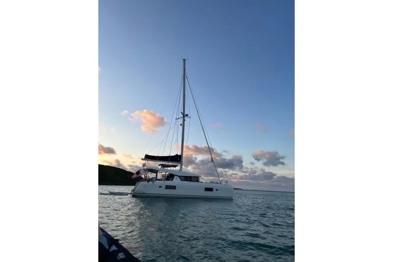 Never Say Never Yacht Photos Pics 2017 Lagoon 42 catamaran sailing at sunset with calm waters and scenic sky.
