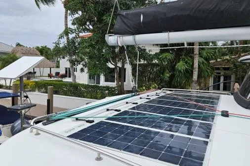 Never Say Never Yacht Photos Pics 2017 Lagoon 42 catamaran with solar panels on deck, docked near tropical foliage.