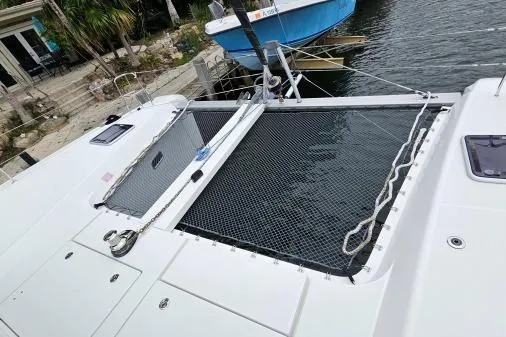 Never Say Never Yacht Photos Pics 2017 Lagoon 42 catamaran with netted deck, docked by the water.