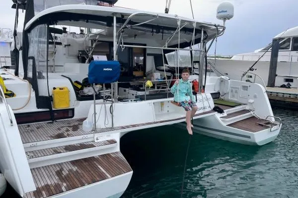 Never Say Never Yacht Photos Pics Child sitting on 2017 Lagoon 42 catamaran, docked at marina, with nautical equipment visible.