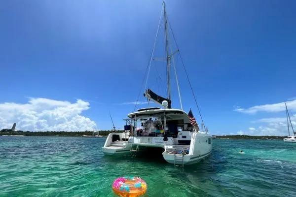 Never Say Never Yacht Photos Pics 2017 Lagoon 42 catamaran anchored in clear turquoise waters under a bright blue sky.