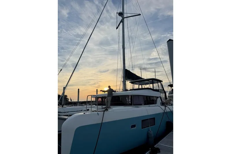 Never Say Never Yacht Photos Pics 2017 Lagoon 42 catamaran docked at sunset with a person on deck.