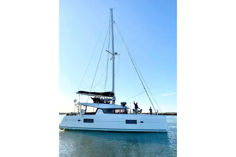 Never Say Never Yacht Photos Pics 2017 Lagoon 42 catamaran sailing on calm waters under clear blue sky.
