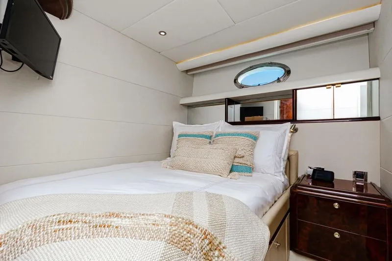 Serendipity Yacht Photos Pics Luxurious bedroom interior of 2001 Lazzara 94 Motor Yacht with cozy bedding and porthole window.