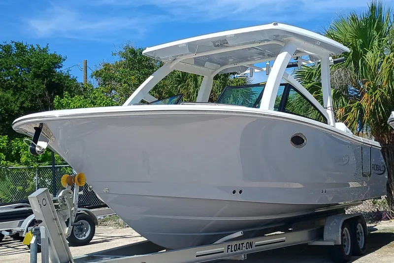 257-155 Yacht Photos Pics 2025 Robalo R257 Dual Console boat on trailer, parked outdoors under clear blue sky.
