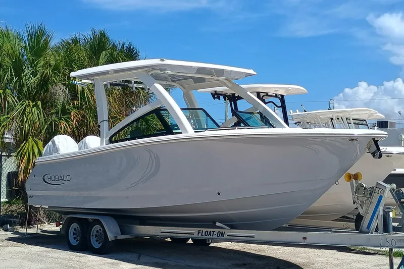 257-155 Yacht Photos Pics 2025 Robalo R257 Dual Console boat on trailer, parked outdoors under clear blue sky.