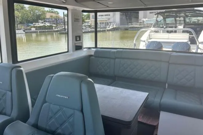  Yacht Photos Pics Interior of 2023 Axopar 37 XC CROSS CABIN with seating and table, docked by water.