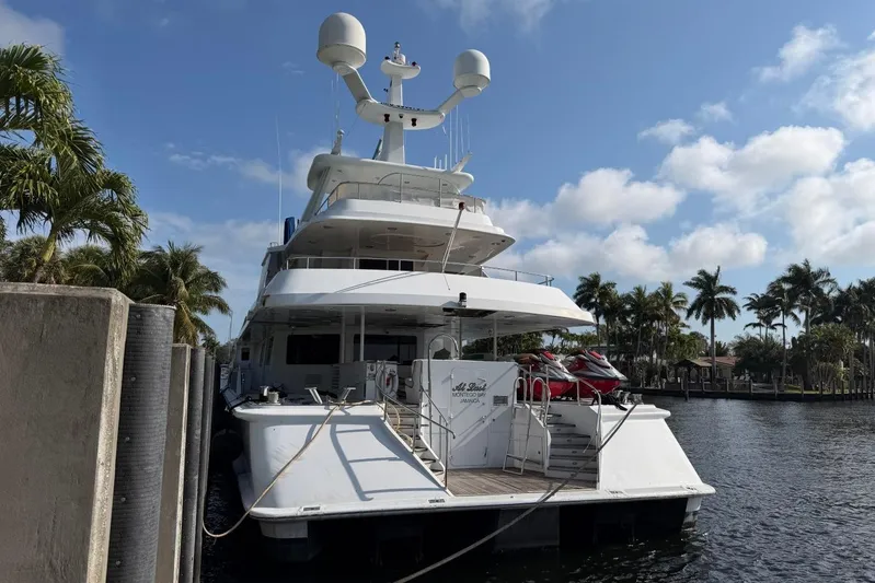  Yacht Photos Pics Luxury Heesen 144 yacht docked, 1990 model, with jet skis, surrounded by palm trees.