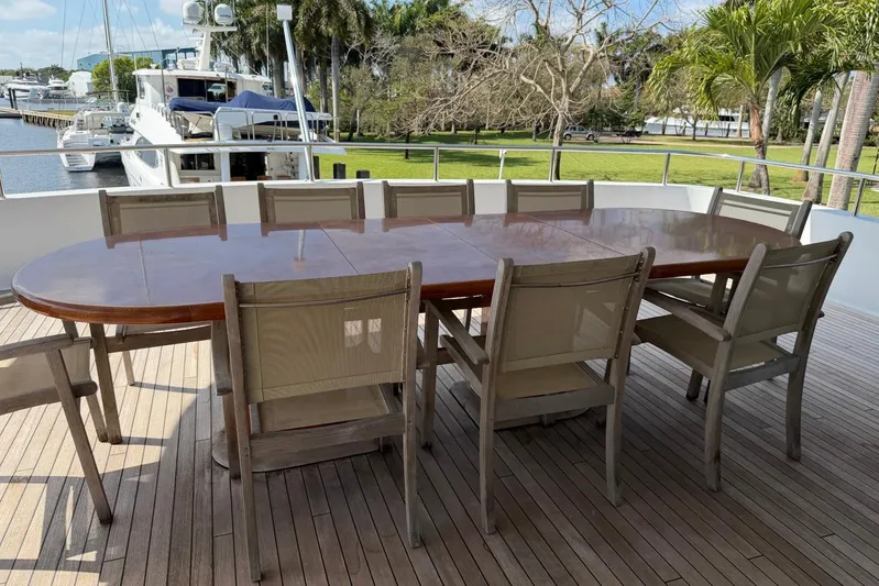  Yacht Photos Pics Outdoor dining area on 1990 Heesen 144 yacht with wooden table and chairs.