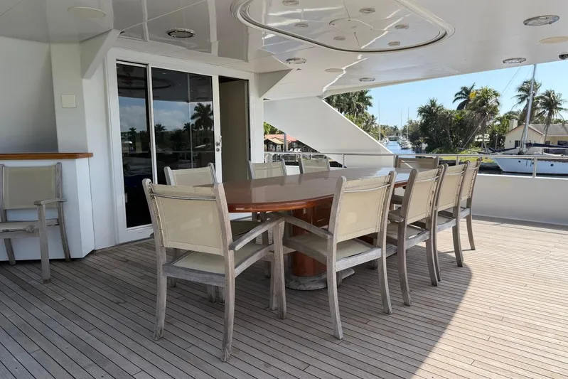  Yacht Photos Pics Outdoor dining area on 1990 Heesen 144 yacht with wooden table and chairs.