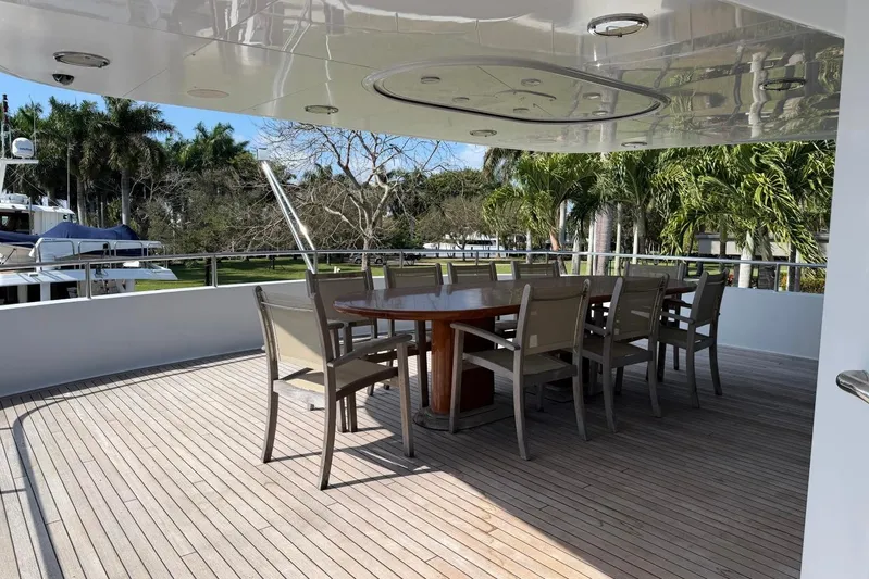  Yacht Photos Pics Outdoor dining area on 1990 Heesen 144 yacht with wooden deck and tropical surroundings.