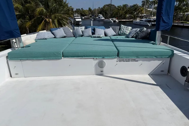  Yacht Photos Pics Luxurious sun pad on 1990 Heesen 144 yacht with cushions and pillows, docked near palm trees.