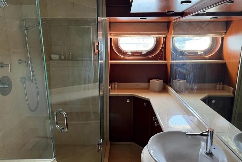  Yacht Photos Pics Luxurious yacht bathroom with glass shower, porthole windows, and elegant wood cabinetry. Heesen 144, 1990.