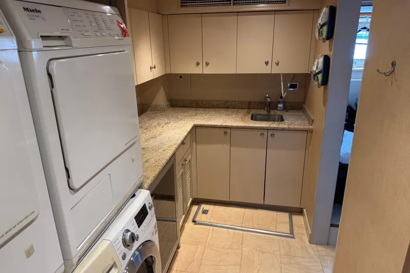  Yacht Photos Pics Laundry room with stacked Miele appliances, beige cabinets, and granite countertops on a Heesen 144 yacht.