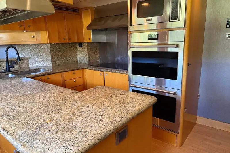  Yacht Photos Pics Modern yacht kitchen with granite countertops, stainless steel appliances, and wooden cabinetry on a 1990 Heesen 144.