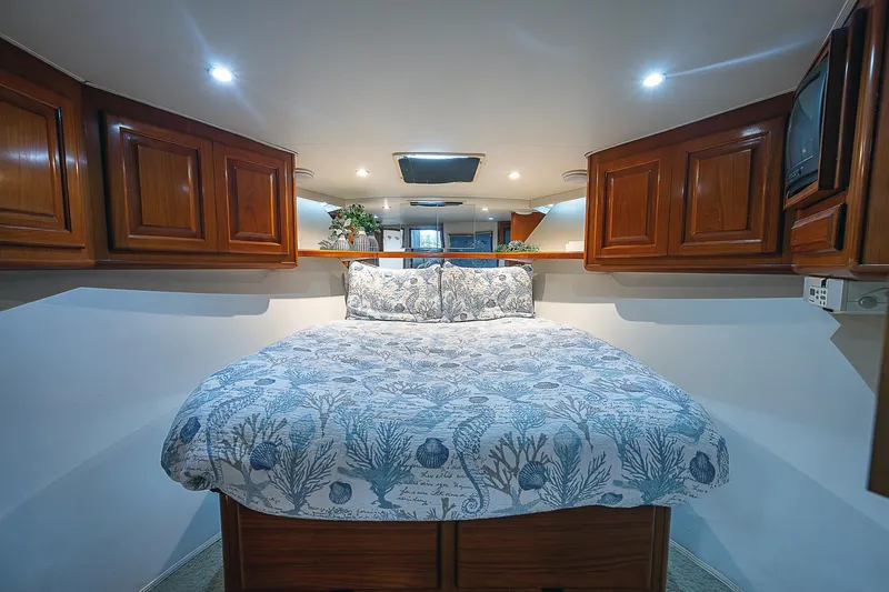  Yacht Photos Pics Cozy bedroom in 1998 Viking 47 Convertible yacht with wooden cabinets and patterned bedding.